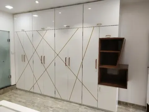 Glossy laminate-faced wardrobe cabinet with decorative gold trim detailing